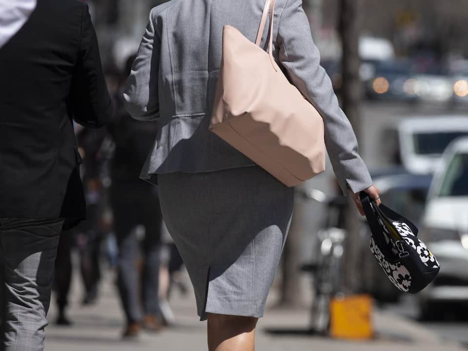 A woman in a business suit is walking on a sidewalk.