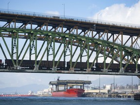 Pictured is a cargo ship as seen from Burrard Inlet March 8, 2022. Foreground Second Narrows rail and road bridges.