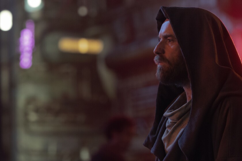 the profile of a bearded man in a hooded cape