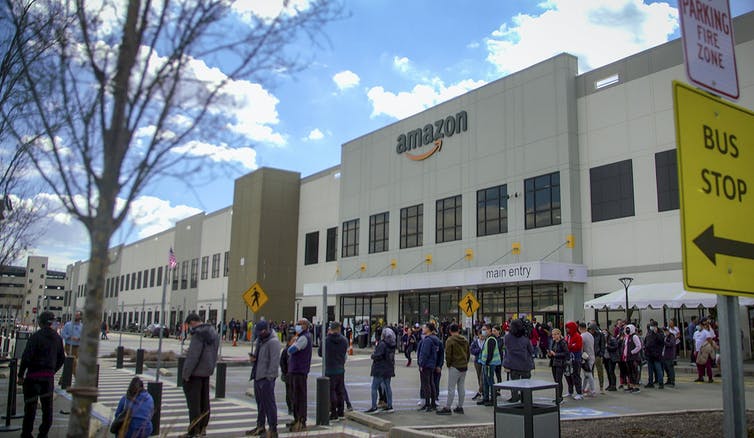 People lining up on a sidewalk outside an Amazon building