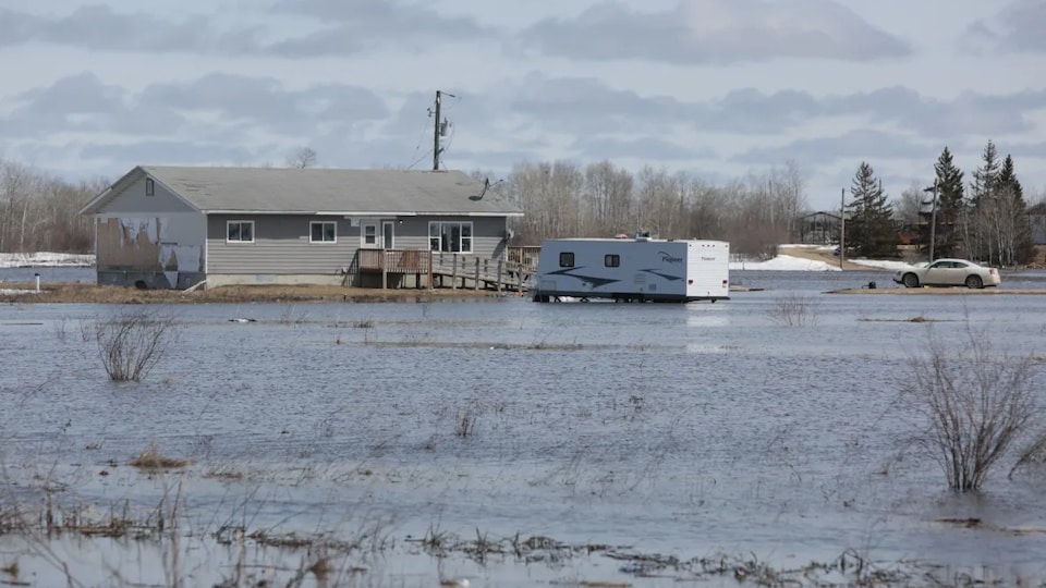 A house, a car and an RV surrounded by water from the spring flood.