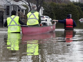 Volunteers from Sauvetage Animal Rescue make their way down a flooded street in Ste-Marthe-sur-le-Lac to rescue two cats and a dog on April 29, 2019.