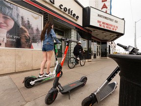 An e-scooter rider and a cyclist travel on the sidewalk along 109 Street at 87 Avenue in Edmonton, on Friday, May 14, 2021.