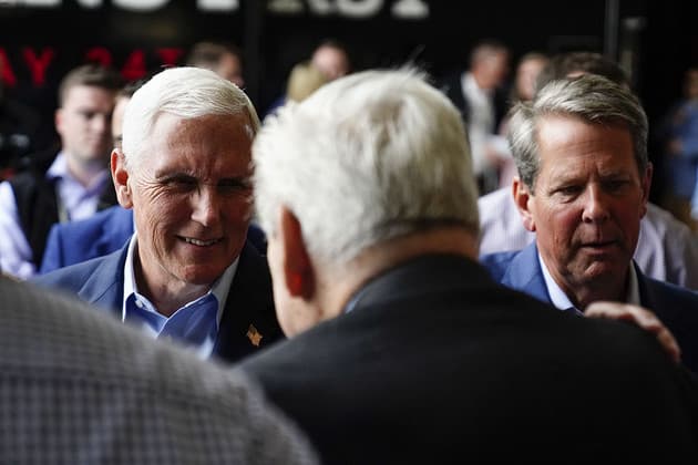Mike Pence and Brian Kemp talk to a person.
