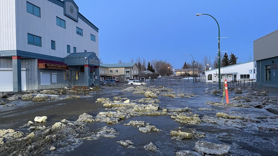 Water and ice can be found on a street in Hay River in front of a three story building.