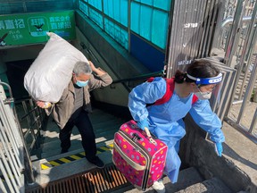 Travelers carrying luggage leave a subway station on the first day of parts of city's subway services summarized in Shanghai, China May 22, 2022.
