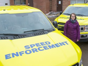 Jessica Lamarre poses with two mobile photo radar trucks that with a bright wrap to make them more visible to motorists.