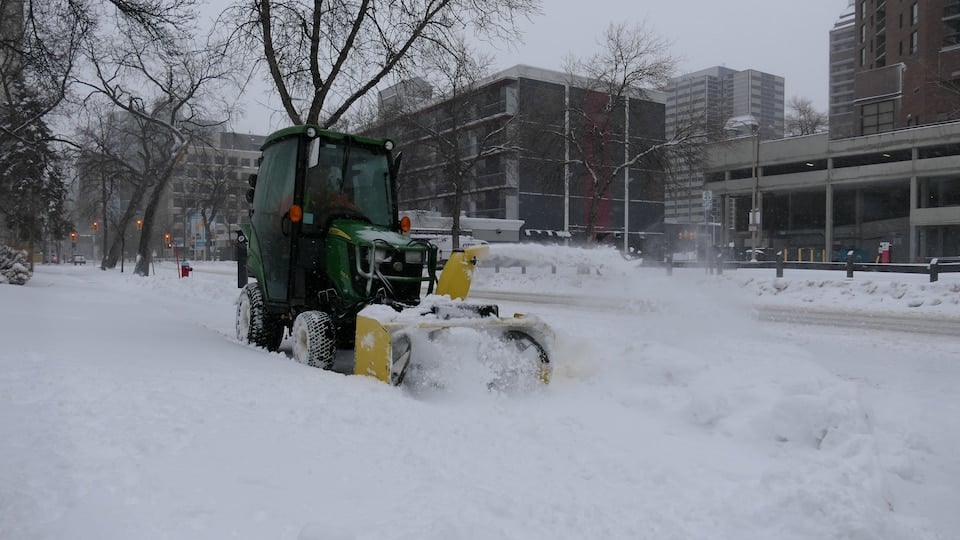 A machine clears snow from a sidewalk in Winnipeg Thursday, April 14, 2022.