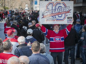 Louis Theberge, a fan of Guy Lafleur, displays a sign as he waits along Canadiens-de-Montréal Ave. on Sunday May 1, 2022, prior to the opening of the Bell Center, where Lafleur's body was lying in state.