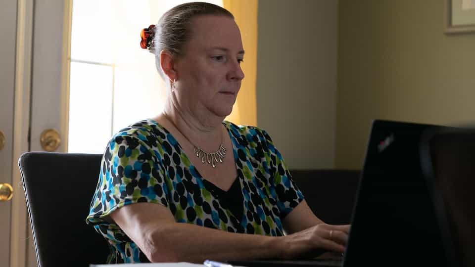 Joanne Gervais sits on a chair and writes on the computer
