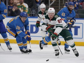 Minnesota Wild's Kirill Kaprizov controls the puck as St. Louis Blues' Robert Thomas (18) and Robert Bortuzzo (41) defend during the first period of an NHL hockey game Saturday, April 16, 2022, in St. Louis.