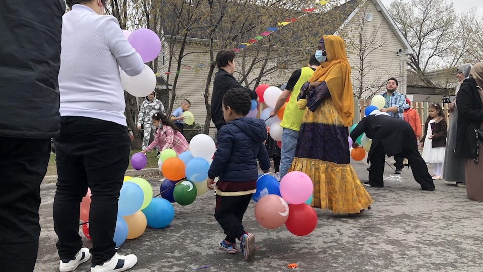 Children and adults at a party, outside, with balloons.