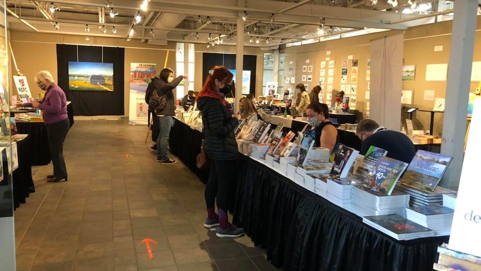 Visitors look at a long table of books.
