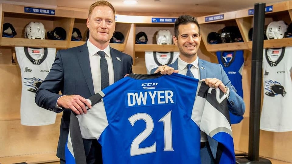 Two men are holding a sweater with Dwyer 21 written on it.