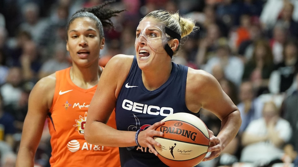 She advances with the basketball in blue, in front of a player in orange. 