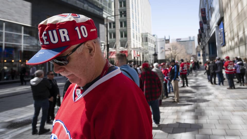 A man, wearing a Canadiens jersey and cap, head bowed.