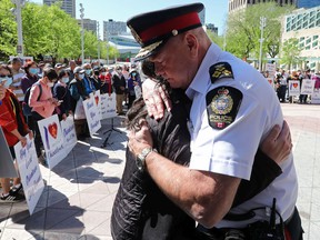 Edmonton police Chief Dale McFee hugs Dr. Holly Mah, Chair of Chinatown and Area Business Association, as they take part in a Chinatown safety rally outside City Hall, in Edmonton, Saturday, May 28, 2022. David Bloom-Postmedia