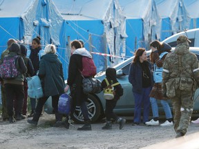 Civilians evacuated from Azovstal steel plant in Mariupol walk accompanied by a member of the International Committee of the Red Cross and a UN staff member, as they arrive at a temporary accommodation center in the village of Bezimenne, during Ukraine-Russia conflict in the Donetsk Region , Ukraine, Friday, May 6, 2022.