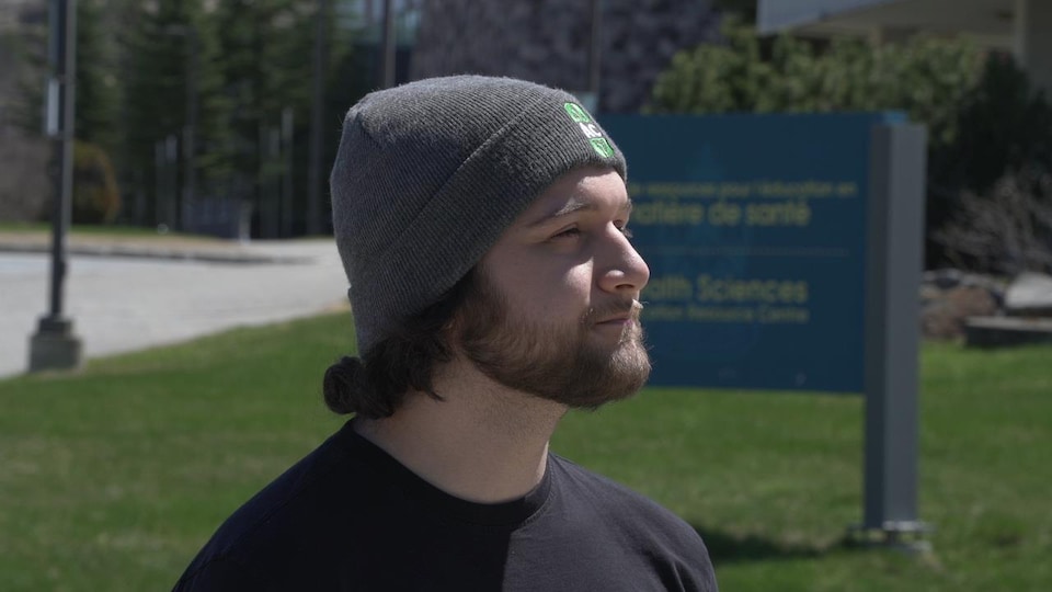 Maxime Cayouette is wearing a gray toque and a black t-shirt