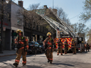 Firefighters walk away from the scene of a fire just north of the intersection of St-Laurent Blvd. and Prince Arthur St. that went from a one-alarm fire to a four-alarm fire very quickly on Saturday, May 7, 2022, in Montréal.  No injuries were reported. 