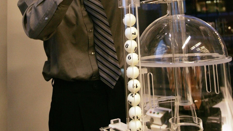 A man inserts numbered ping-pong balls into a machine.