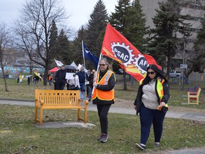Protesters march from Memorial Park towards Tom Davies Square on Sunday afternoon as part of a May Day rally that called on candidates in the upcoming provincial election to value workers and their families.