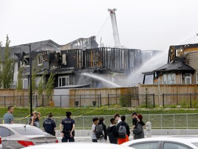 Firefighters pour water on homes severely damaged by fire in the northwest community of Evanston on Friday, June 3, 2022.