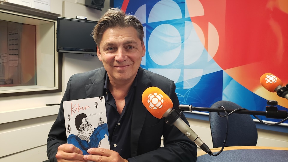 Michel Jean in the studio holds his most recent book.