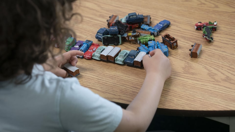 A child is playing with toy cars on a table.