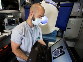 Medical Radiological Technologist Jeremy Hayes looks at a CT scan as he poses for a photo in the University of Alberta Hospital Stroke Ambulance, in Edmonton Friday June 10, 2022. The ambulances onboard CT scanner is visible behind Hayes.