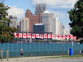 A pedestrian walks past Flags of Remembrance on the Windsor riverfront on Sept.  23, 2019, where 128 flags are flying representing 128,000 Canadian soldiers and RCMP who have died or are missing since the Boer War.  The Detroit, Michigan skyline is shown across the Detroit River.