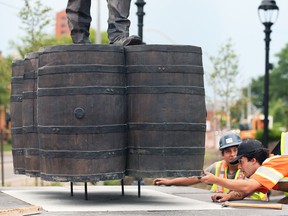Workers install a bronze statue of Hiram Walker at the corner of Riverside Drive and Devonshire Road on Monday, June 20, 2022.