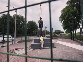A worker guides a bronze statue of Hiram Walker at the corner of Riverside Drive and Devonshire Road on Monday, June 20, 2022.
