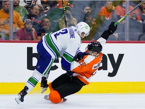 Philadelphia Flyers' James van Riemsdyk, right, and Vancouver Canucks' Jack Rathbone collide during the second period of an NHL hockey game, Friday, Oct. 15, 2021, in Philadelphia.