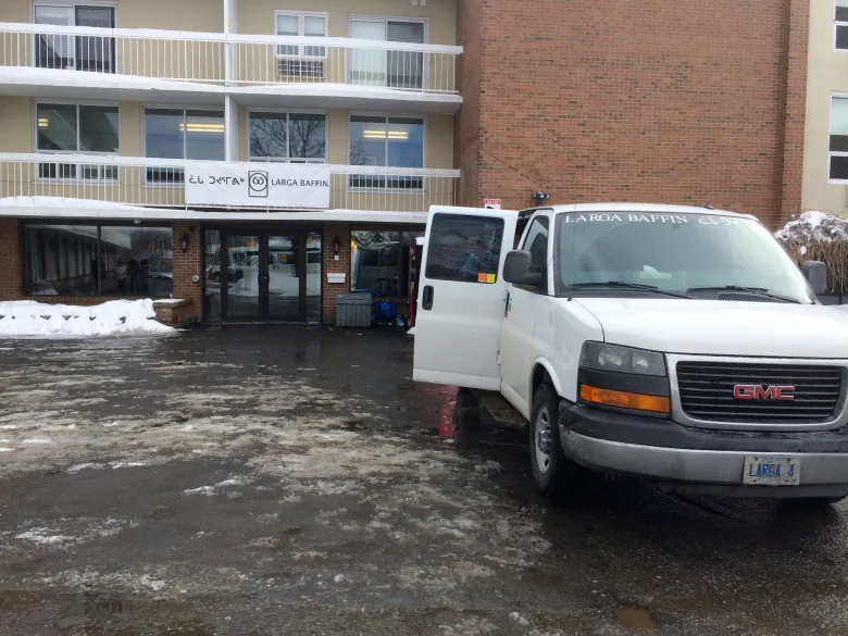 A white van parked outside of a brick building.