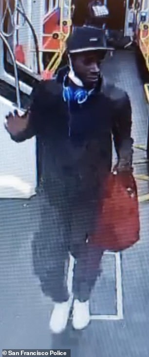 The footage shows a black man wearing a black hoodie and jeans, white sneakers and a black baseball cap with blue headphones around his neck and a red backpack.