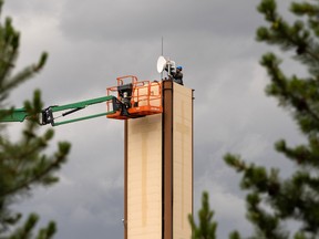 A worker services a dish on the top of a tower at Concordia University while a thunderstorm forms in the distance in Edmonton, on Wednesday, Nov. 22, 2022.