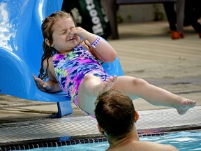 Aubree Richard (5) holds her nose as she slides into summer at Queen Elizabeth Outdoor Pool in Edmonton on Wednesday, June 22, 2022. The pool is the first of the outdoor pools to open in the city.