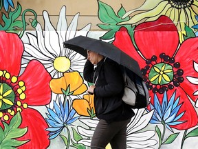 A pedestrian makes their way through the rain along 97 Street near 103 Avenue, in Edmonton Tuesday, June 21, 2022.