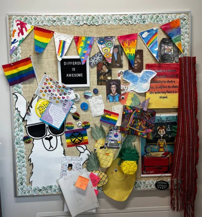 This picture is of a school bulletin board that features Pride flags and sayings, like ‘love is love.’