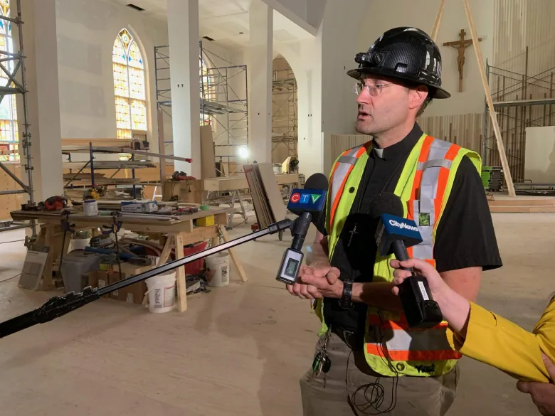A man in a hardhat and construction vest stands inside a church.
