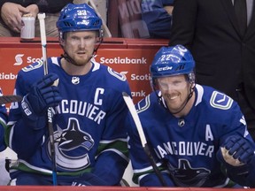 Vancouver Canucks Henrik Sedin (33) and his brother and teammate Daniel Sedin (22) look on from the bench during second period NHL action against the Vegas Golden Knights at Rogers Arena in Vancouver, Tuesday, April 3, 2018.