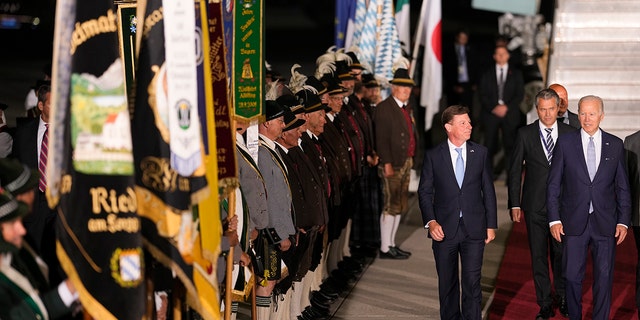 US President Joe Biden, right, waves as he walks past Bavarian Mountain Riflemen and traditional patrons after his arrival at Franz-Josef-Strauss Airport near Munich, Germany, Saturday, June 25, 2022. , before the G7 summit.  Biden is in Germany to attend a summit of the Group of Seven of leaders of the world's major industrialized nations.  (AP Photo/Markus Schreiber)