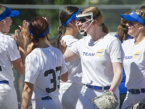 Teenaged pitcher Morgan Reimer, wearing protective cage mask, high-fives BC teammates during Canada Cup play at Softball City in South Surrey on Sunday.