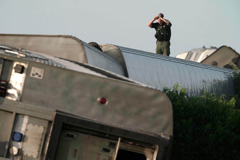 A law enforcement officer inspects the scene of an Amtrak train that derailed after colliding with a dump truck Monday, June 27, 2022, near Mendon, Missouri.