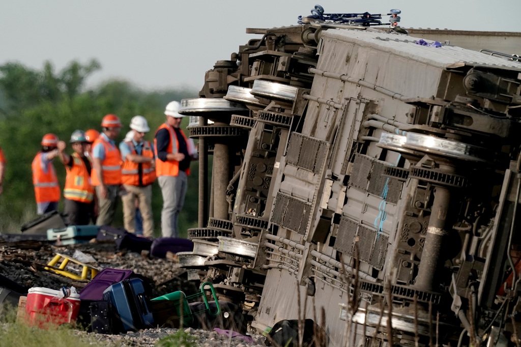 Workers inspect the scene of an Amtrak train that derailed after colliding with a dump truck Monday, June 27, 2022, near Mendon, Mo. (AP Photo/Charlie Riedel)