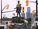 Workers install a bronze statue of Hiram Walker at the corner of Riverside Drive and Devonshire Road on Monday, June 20, 2022.
