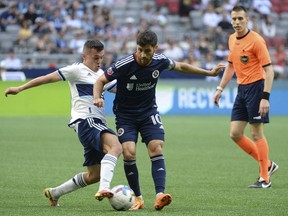 Vancouver Whitecaps midfielder Andres Cubas (20) challenges New England Revolution midfielder Carles Gil (10) during the first half at BC Place.
