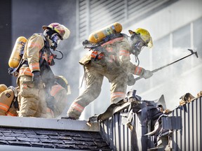 Firefighters work to open the roof of a burning building at the corner of St-Antoine and de la Montagne Sts.  in Montreal Tuesday June 28, 2022.