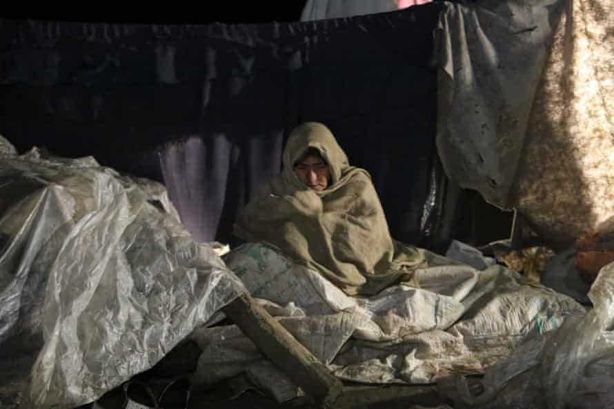 A woman in Paktika province made homeless by the earthquake tries to keep warm.